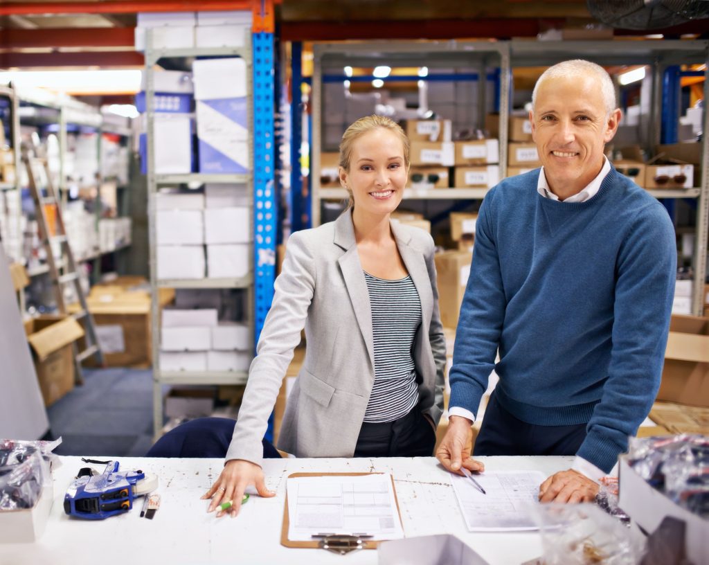 Two Coworkers in the middle of discussing notes smiling for a photo.