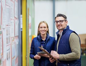 Coworkers sharing notes as they smile at someone approaching them.