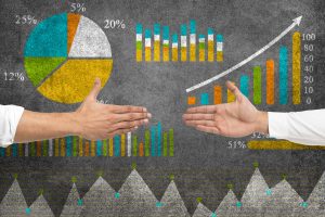 Hands about to shake in front of chalkboard full of business analytics.